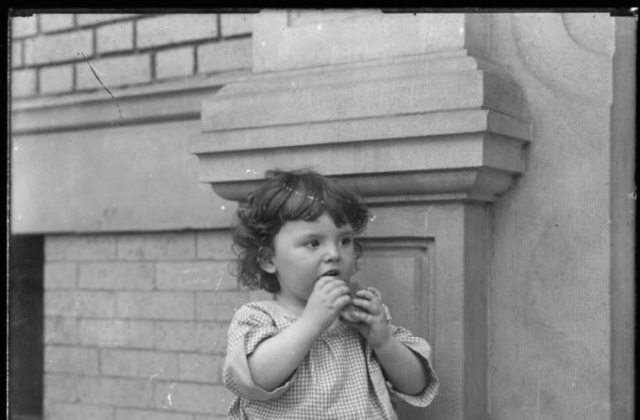 Toddler on front stoop of Vermilyea Avenue apartment building, photo by William Hassler, undated, NYHS.